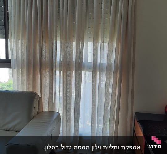 וילון שקוף בהיר תלוי על חלון גדול